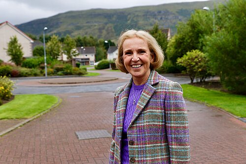 Susan Murray smiling in a purple and green tartan jacket.