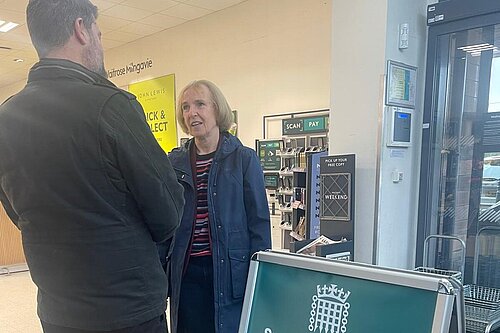 Susan Murray talking with a resident next to an A board with the words Susan Murray MP Advice Surgery.