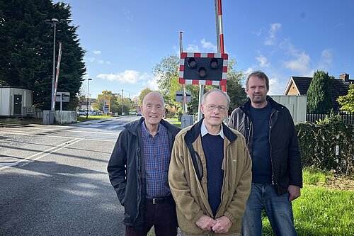 Ian Cuthberton, Richard Watson, and Andrew Hollyer standing by a level crossing in Haxby